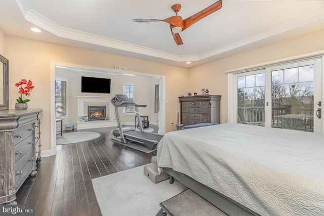 bedroom featuring ceiling fan, access to outside, a tray ceiling, dark wood-type flooring, and ornamental molding