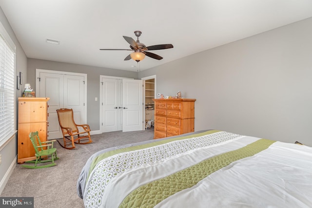 bedroom featuring ceiling fan, two closets, and carpet floors