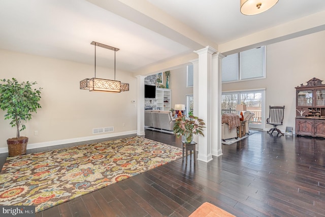 interior space with decorative columns, dark wood-type flooring, and a high ceiling