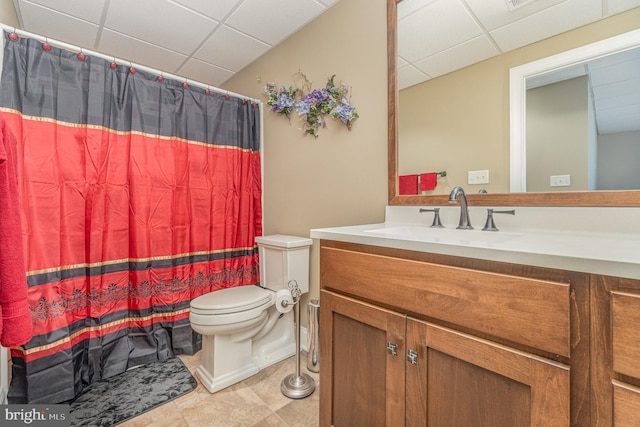 bathroom featuring a drop ceiling, toilet, vanity, and a shower with curtain