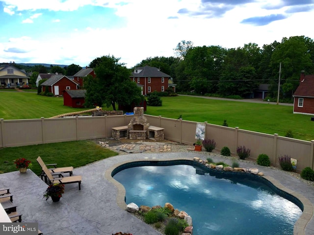 view of pool featuring a patio area, a yard, and an outdoor stone fireplace