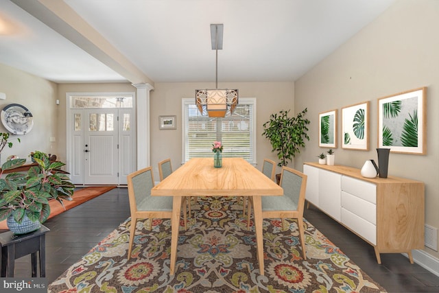 dining space featuring dark hardwood / wood-style floors and ornate columns