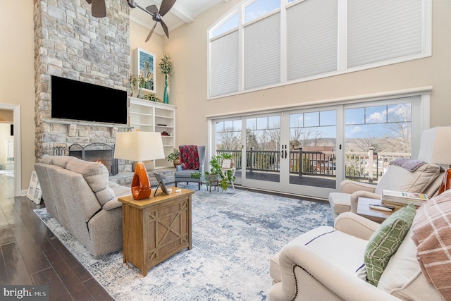 living room featuring a fireplace, ceiling fan, a healthy amount of sunlight, and beam ceiling