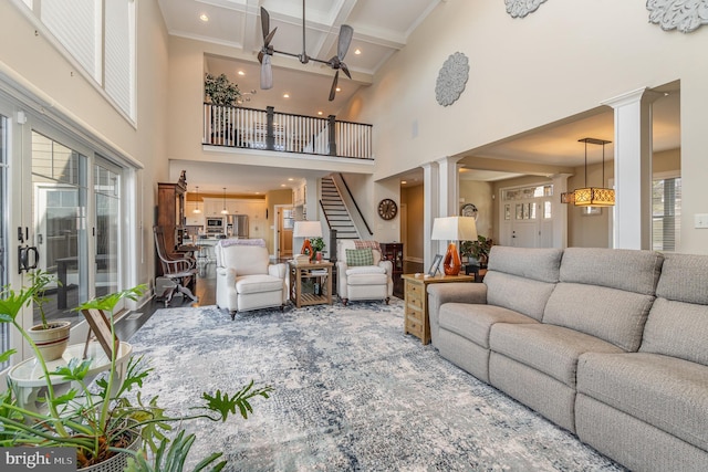 living room featuring a high ceiling, ornate columns, and beamed ceiling