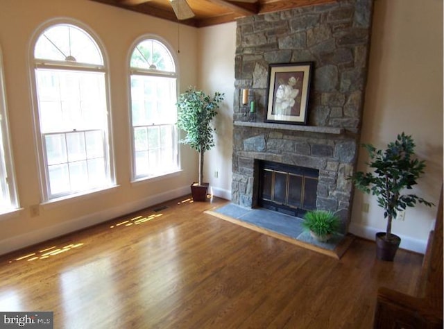 living room with ceiling fan, wood-type flooring, and a stone fireplace