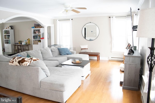 living room featuring light hardwood / wood-style floors, baseboard heating, ornamental molding, and ceiling fan