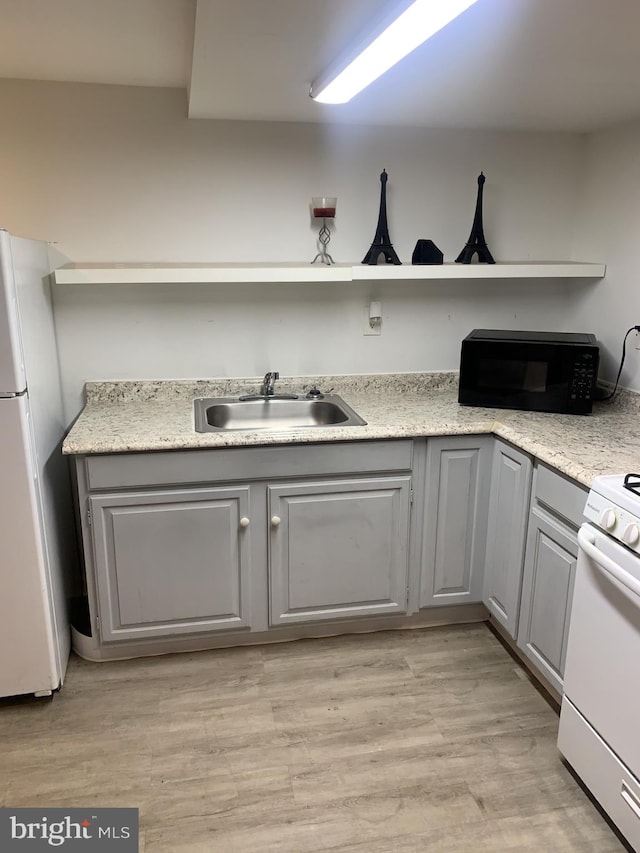 kitchen with gray cabinetry, sink, white appliances, and light hardwood / wood-style floors