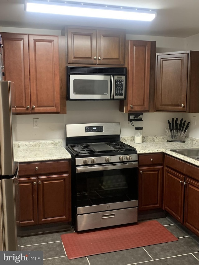 kitchen featuring appliances with stainless steel finishes, sink, and dark tile patterned floors