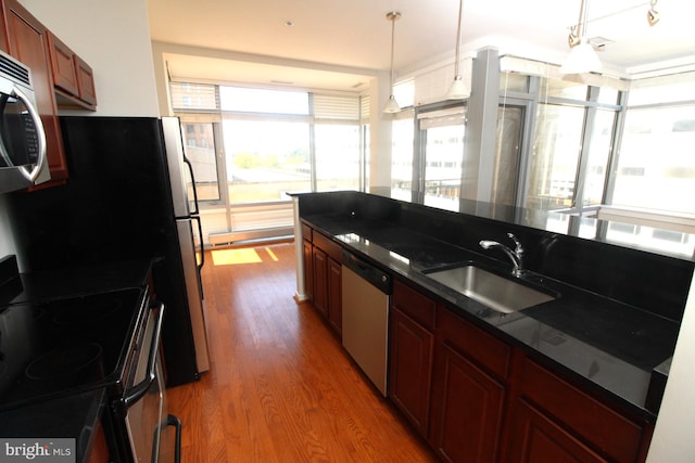 kitchen featuring hanging light fixtures, appliances with stainless steel finishes, sink, and hardwood / wood-style flooring