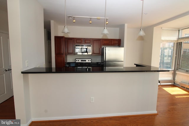 kitchen featuring hardwood / wood-style flooring, hanging light fixtures, and appliances with stainless steel finishes