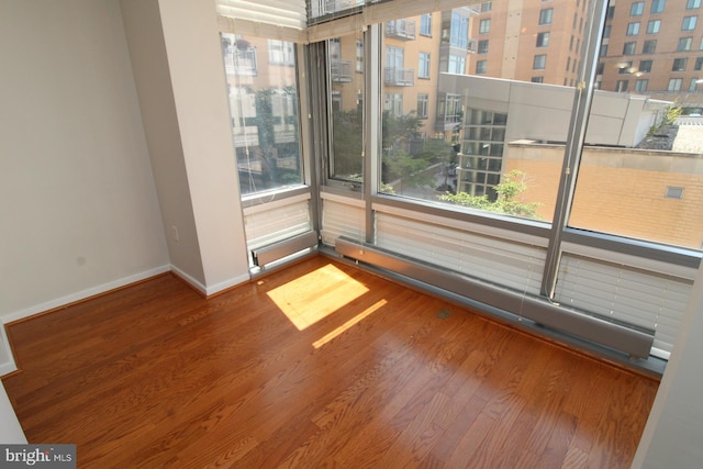 spare room featuring baseboard heating and hardwood / wood-style flooring