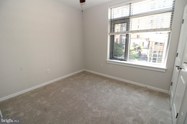 spare room featuring light carpet, a healthy amount of sunlight, and ceiling fan