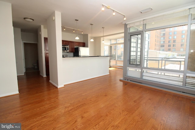 kitchen with hardwood / wood-style flooring, fridge, pendant lighting, and a wall of windows