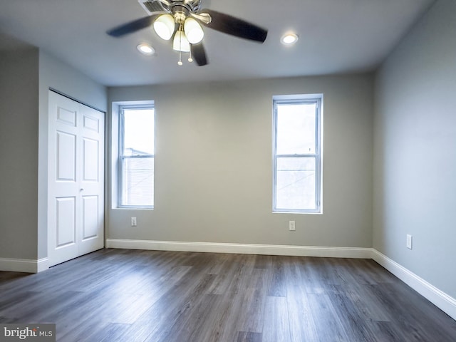 empty room with dark hardwood / wood-style flooring, ceiling fan, and a healthy amount of sunlight