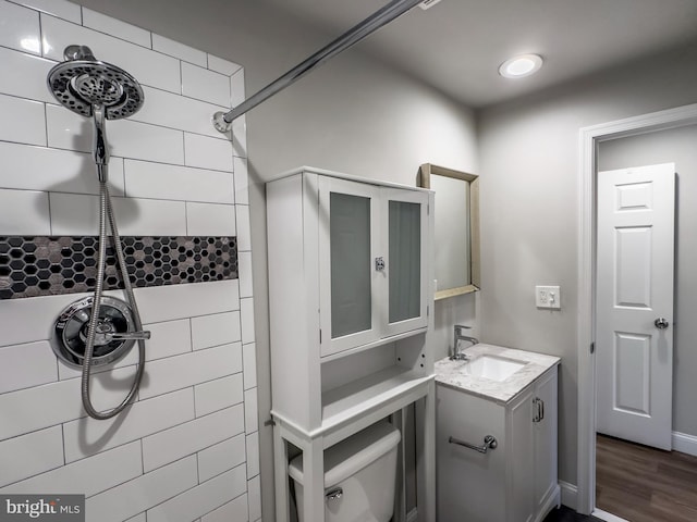 bathroom with hardwood / wood-style floors, vanity, and a tile shower