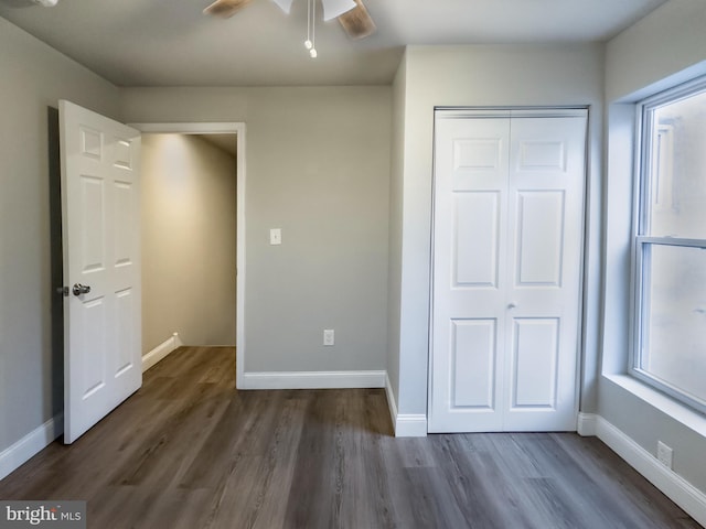 unfurnished bedroom with ceiling fan, dark hardwood / wood-style flooring, and a closet