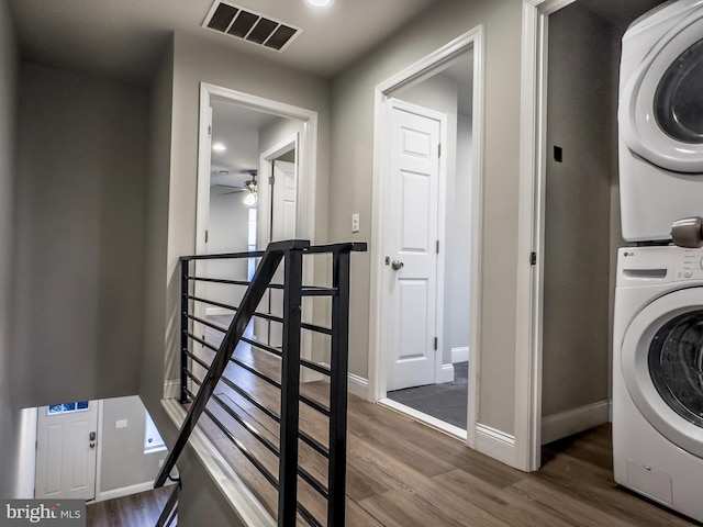 laundry room with ceiling fan, stacked washer / drying machine, and dark hardwood / wood-style floors