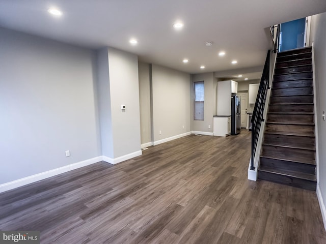 basement featuring dark hardwood / wood-style flooring and stainless steel fridge