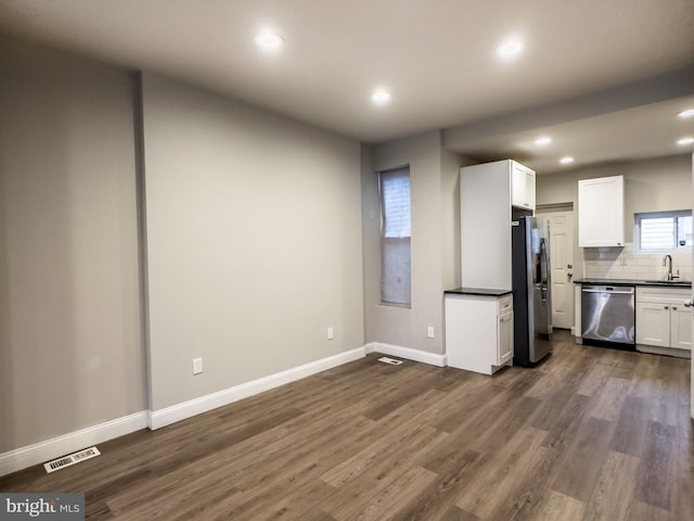 kitchen with white cabinetry, sink, decorative backsplash, stainless steel appliances, and dark wood-type flooring