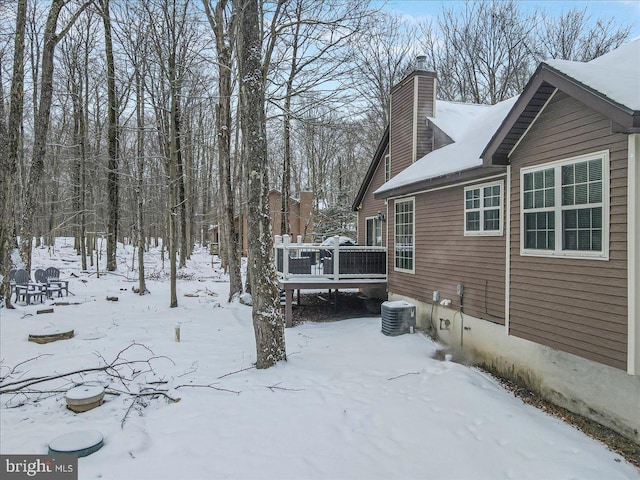 view of snow covered exterior with central AC unit and a deck