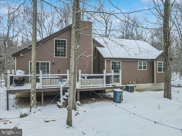 snow covered house with a wooden deck and cooling unit