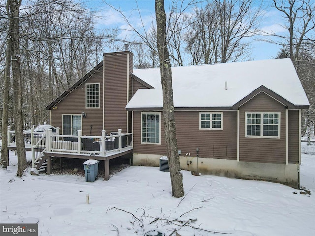 snow covered back of property with a deck