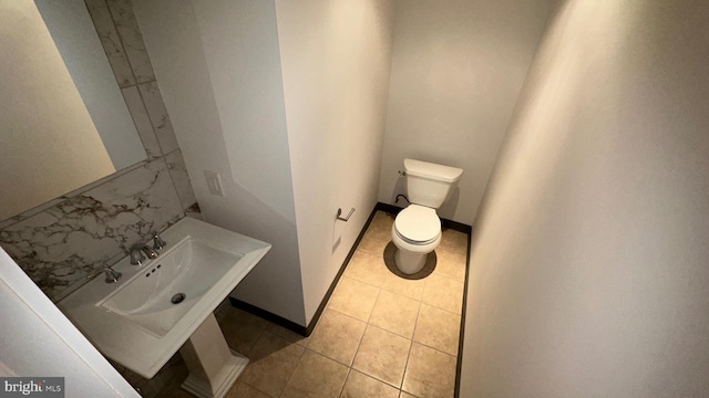 bathroom with toilet, sink, and tile patterned floors