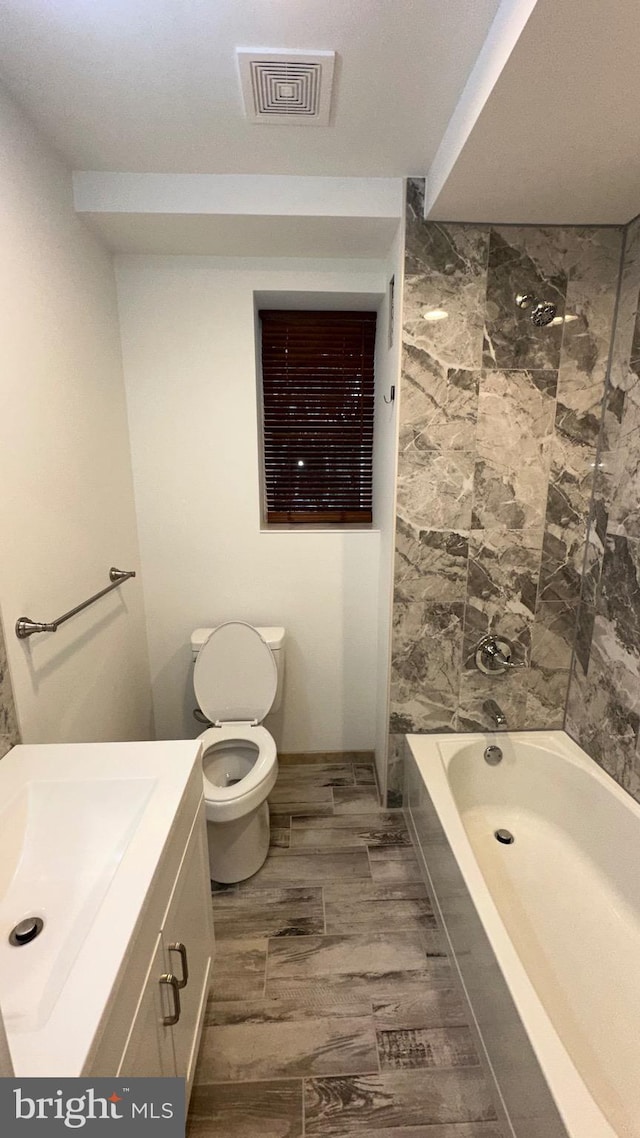 full bathroom with toilet, tiled shower / bath combo, and vanity