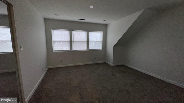 bonus room featuring plenty of natural light and dark colored carpet