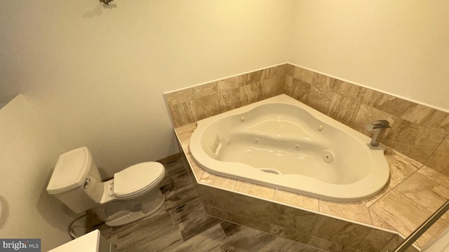 bathroom featuring toilet and a relaxing tiled tub