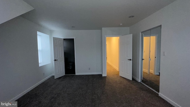 unfurnished bedroom featuring a closet and dark carpet