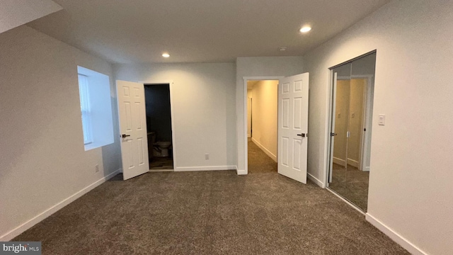 unfurnished bedroom with a closet and dark carpet