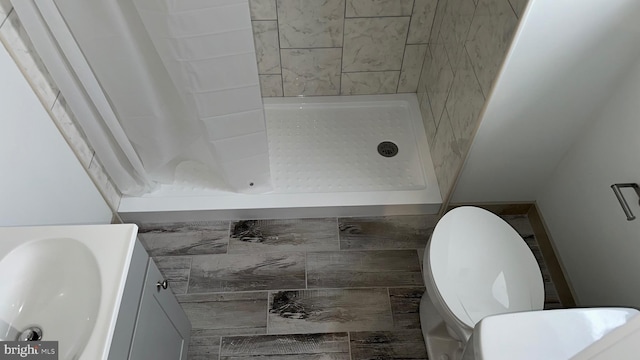 bathroom featuring toilet, vanity, and tiled shower