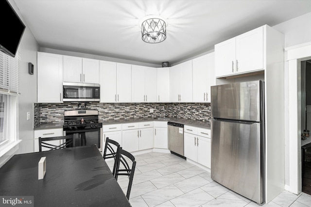 kitchen with backsplash, stainless steel appliances, and white cabinets