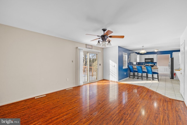 unfurnished living room featuring ceiling fan and light wood-type flooring