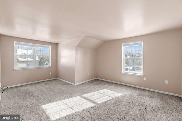 additional living space featuring vaulted ceiling and light colored carpet