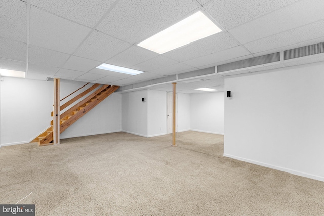 basement featuring a drop ceiling and carpet