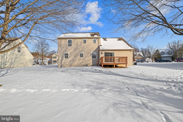 snow covered back of property featuring a deck