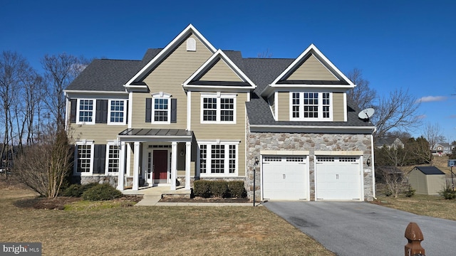 view of front facade with a garage, stone siding, driveway, and a front lawn