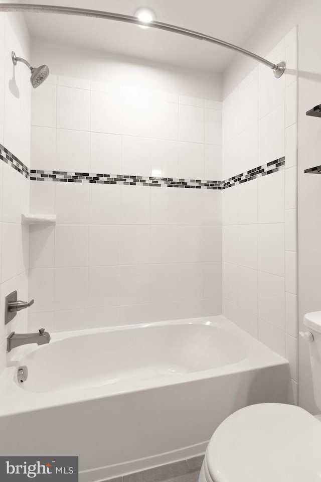 bathroom with toilet and tiled shower / bath