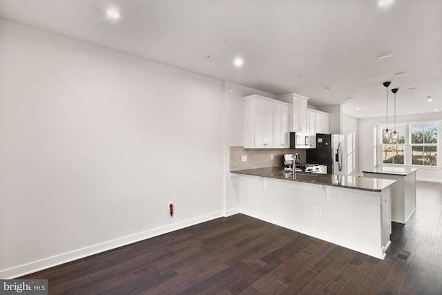 kitchen with kitchen peninsula, white cabinetry, hanging light fixtures, appliances with stainless steel finishes, and a breakfast bar area