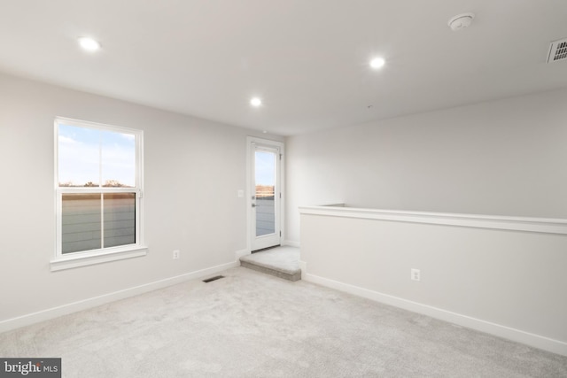 unfurnished room featuring light carpet and plenty of natural light