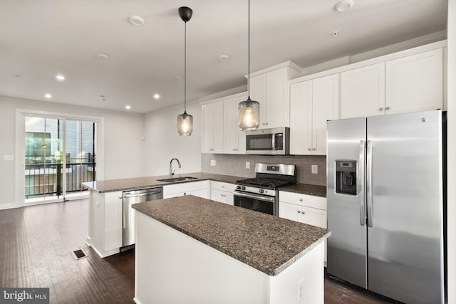 kitchen with a kitchen island, kitchen peninsula, sink, stainless steel appliances, and white cabinets