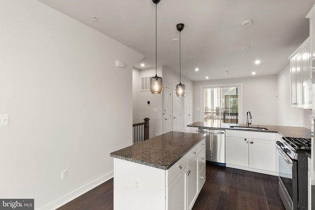 kitchen featuring decorative light fixtures, a kitchen island, sink, white cabinetry, and appliances with stainless steel finishes