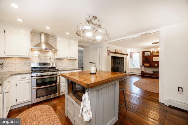 kitchen featuring double oven range, white cabinetry, wall chimney exhaust hood, and dark hardwood / wood-style floors