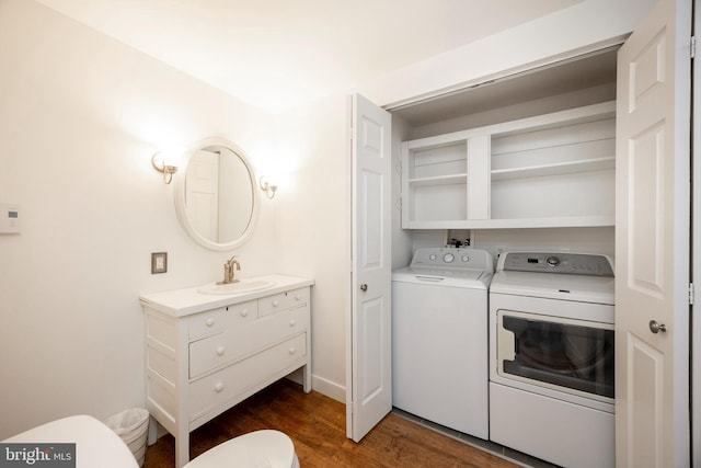 clothes washing area with dark hardwood / wood-style flooring, sink, and washing machine and clothes dryer