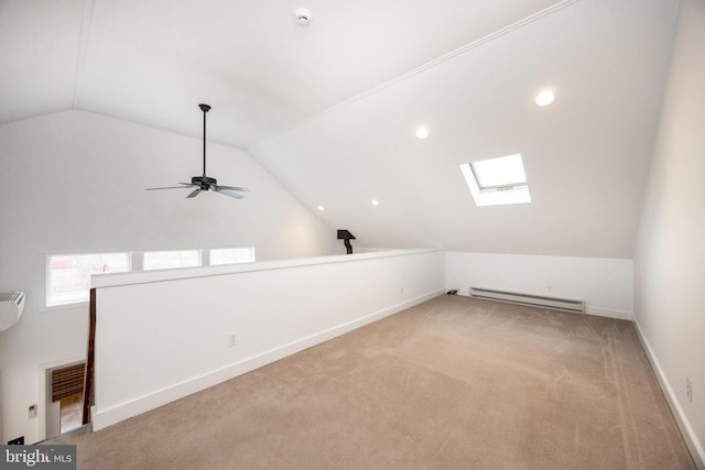 bonus room featuring ceiling fan, light colored carpet, a baseboard heating unit, and vaulted ceiling with skylight