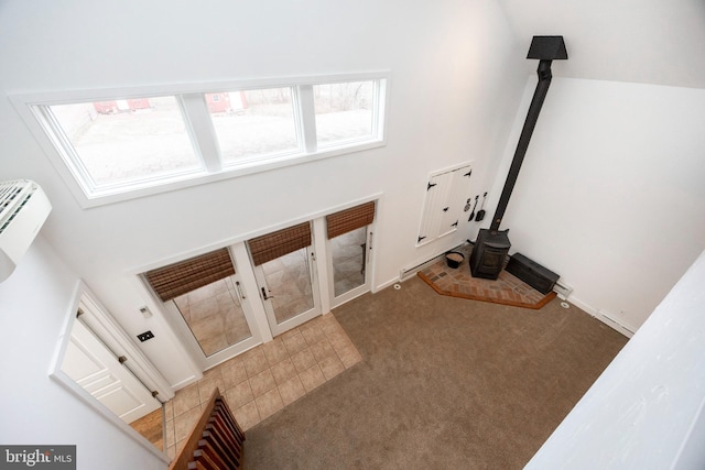 interior space featuring a wood stove, a wall unit AC, and carpet flooring