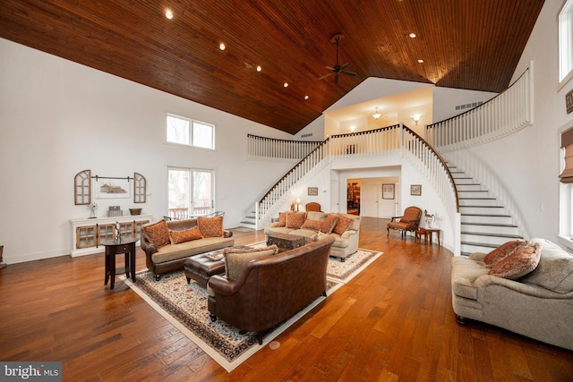 living room featuring ceiling fan, a towering ceiling, wood ceiling, and dark hardwood / wood-style floors