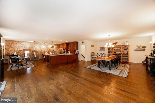 dining area featuring rail lighting, dark hardwood / wood-style flooring, and an inviting chandelier